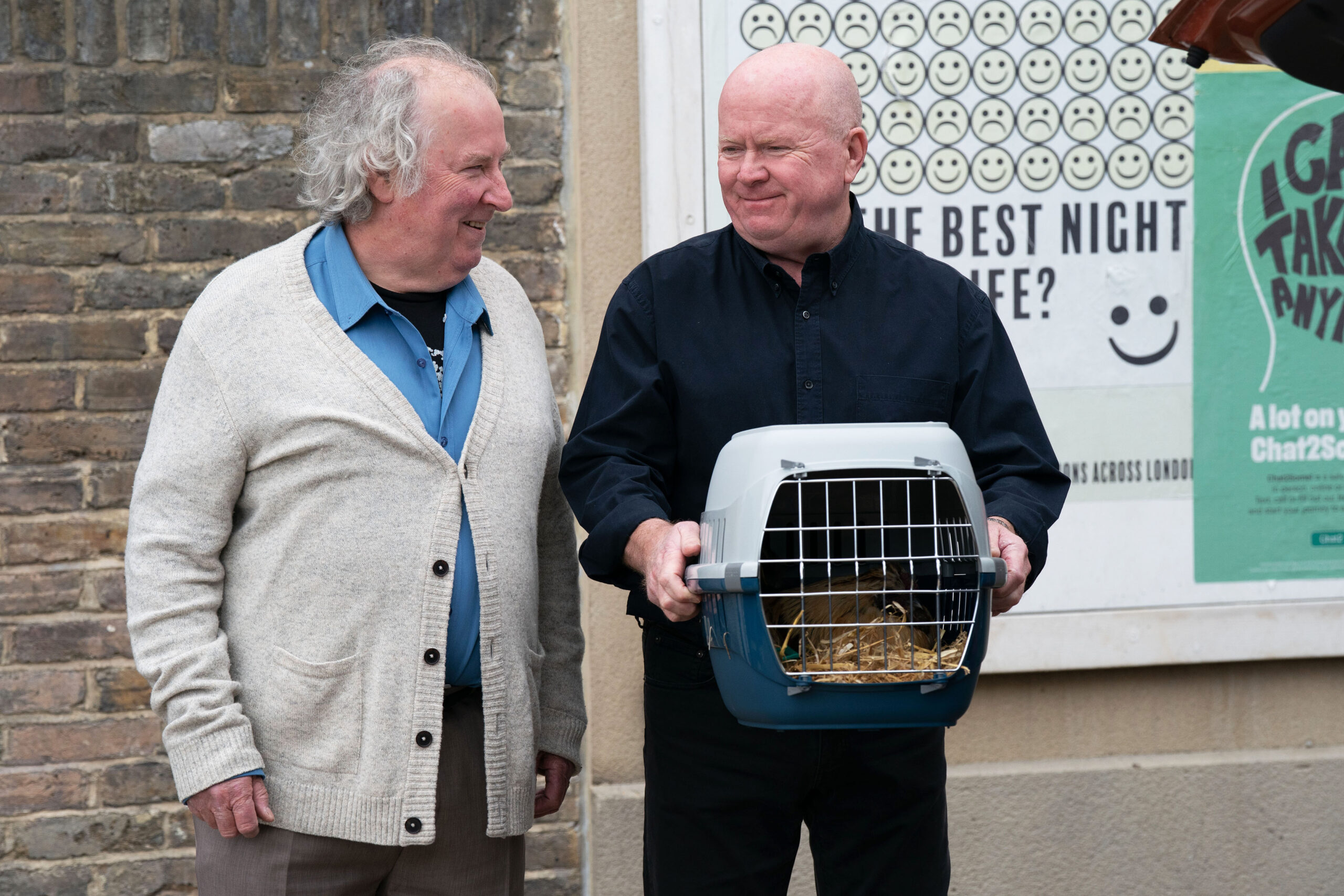 Phil and Nigel exchange a glance as he holds one of Julie's chickens