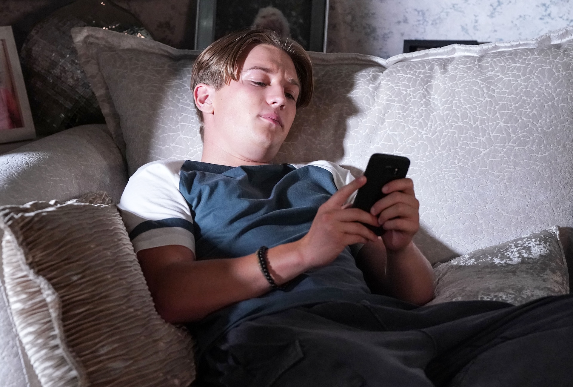 Joel looks at his phone in EastEnders