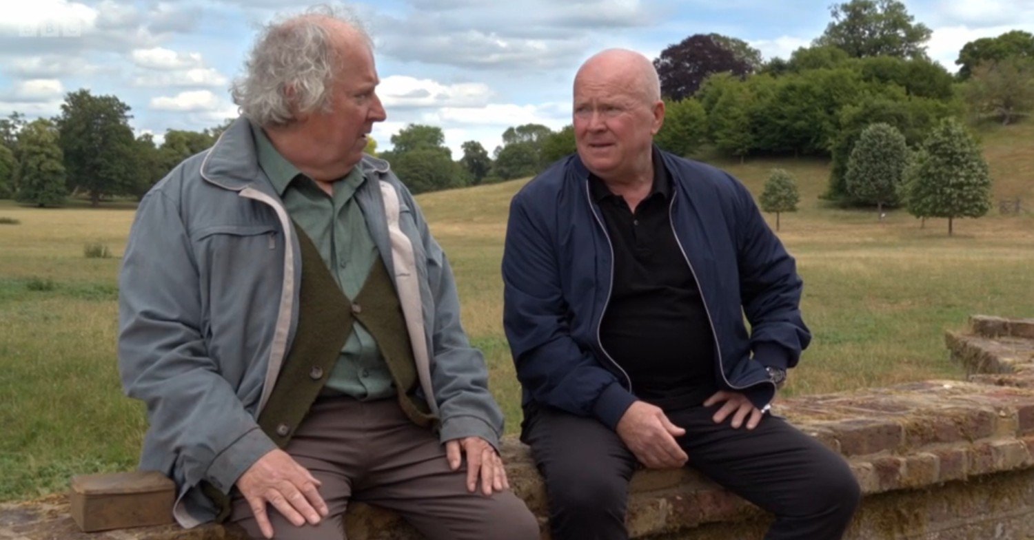 Nigel and Phil sit on a wall, talking