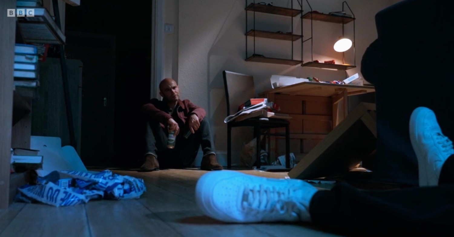 Teddy drinks a beer while Okie lies dead in the corner 