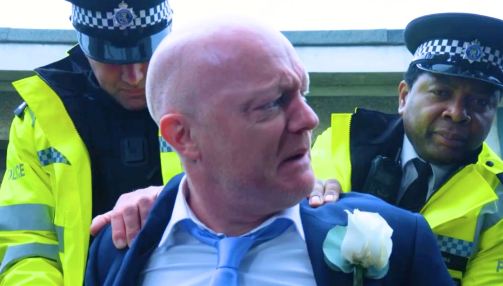 Max looks upset as he's arrested by the police