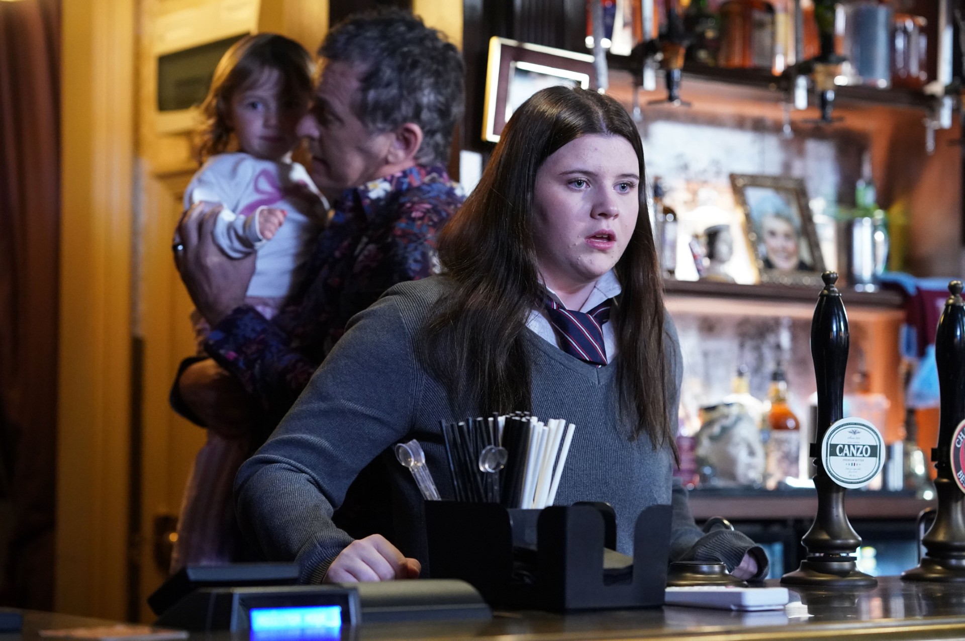 Lily looks angry behind the bar of The Vic