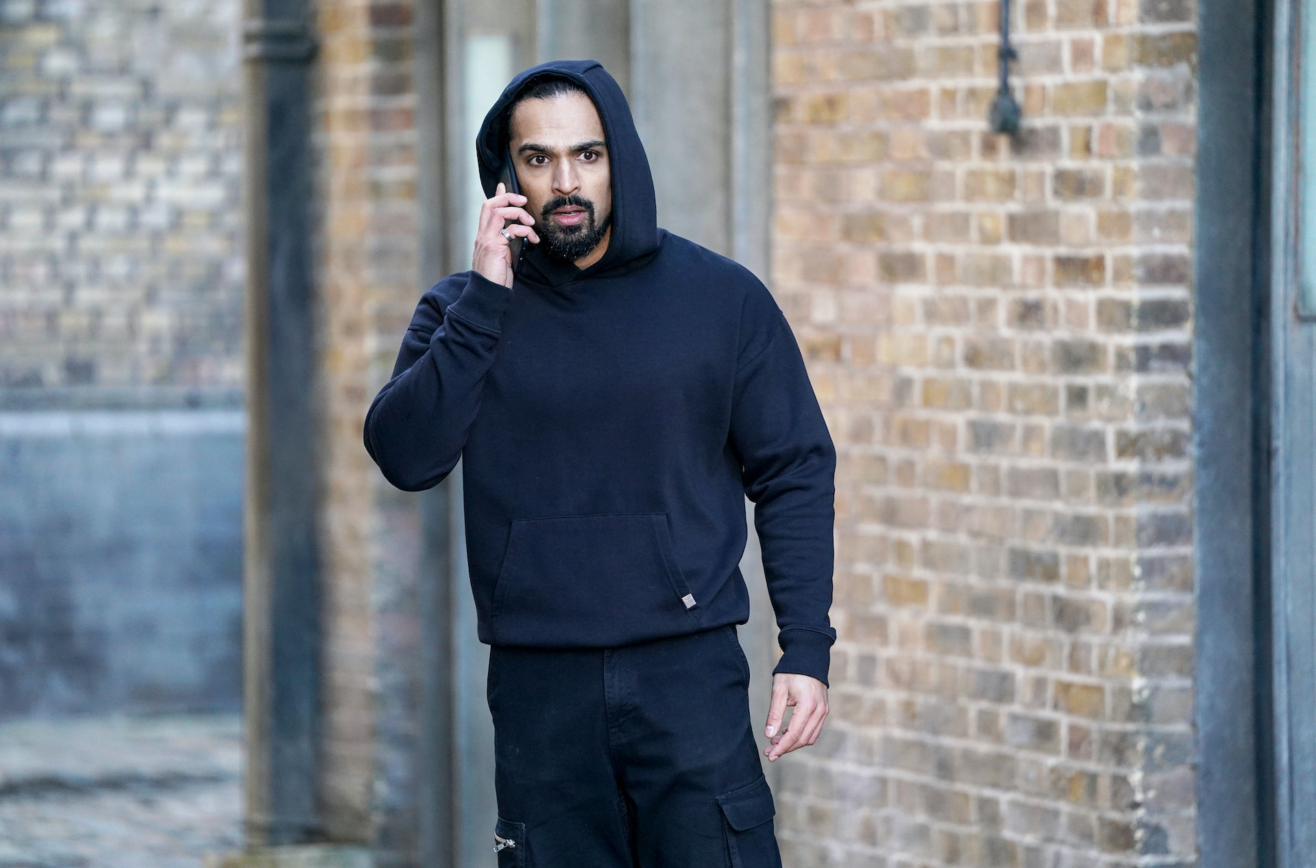 Ravi on the phone looking shocked in EastEnders spoilers