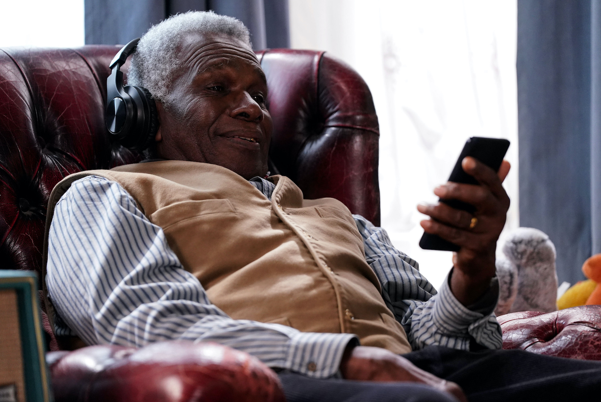 Patrick looking at a phone with headphones on and smiling 