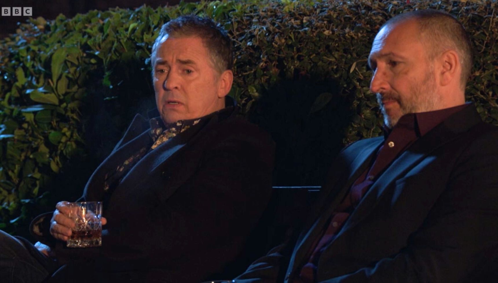 Alfie and Ross chat on a bench in the Square in EastEnders 