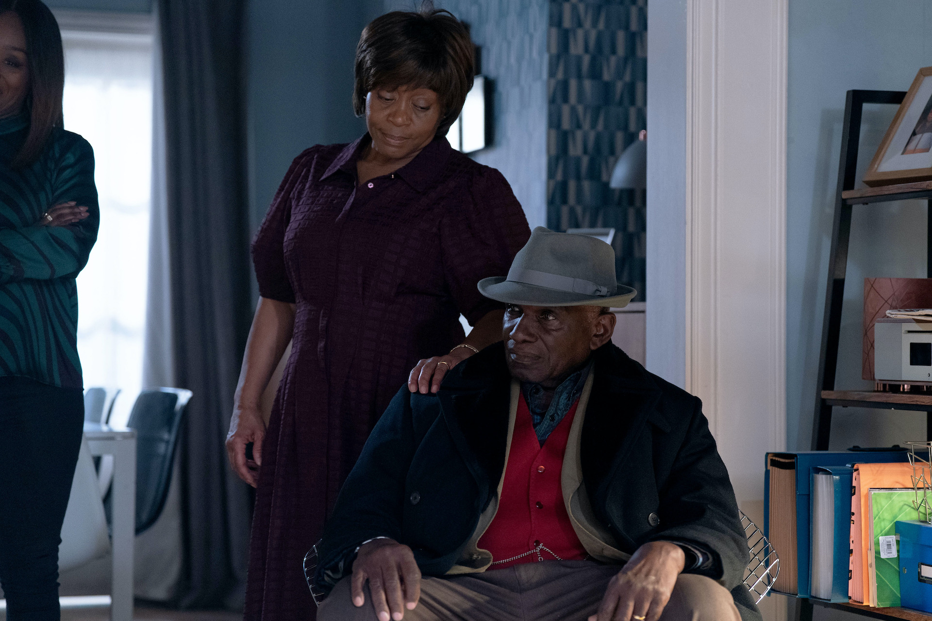 Yolande with her hand on Patrick's shoulder as he looks stressed 