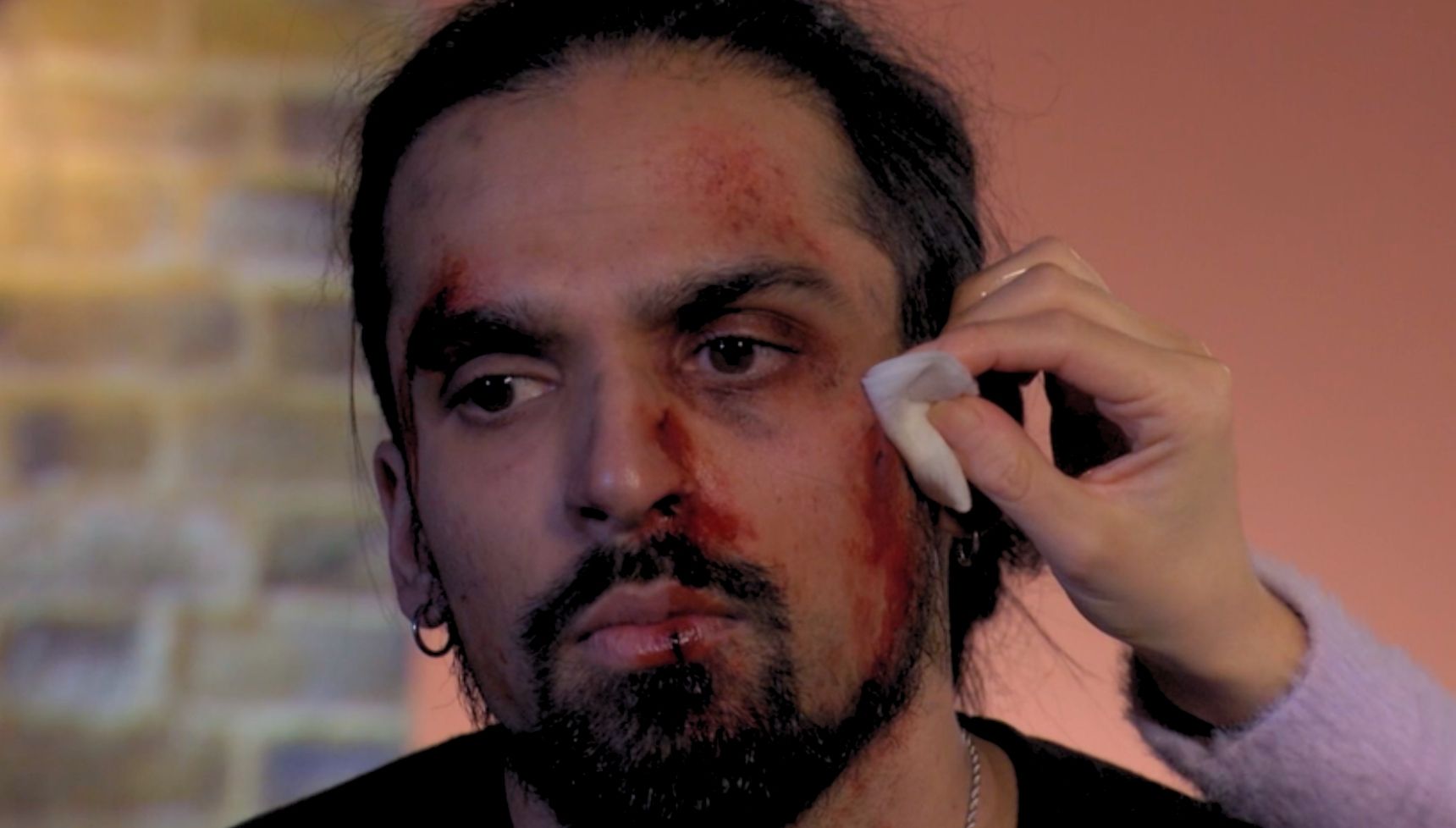 Priya cleans Ravi's wounds at home in the living room