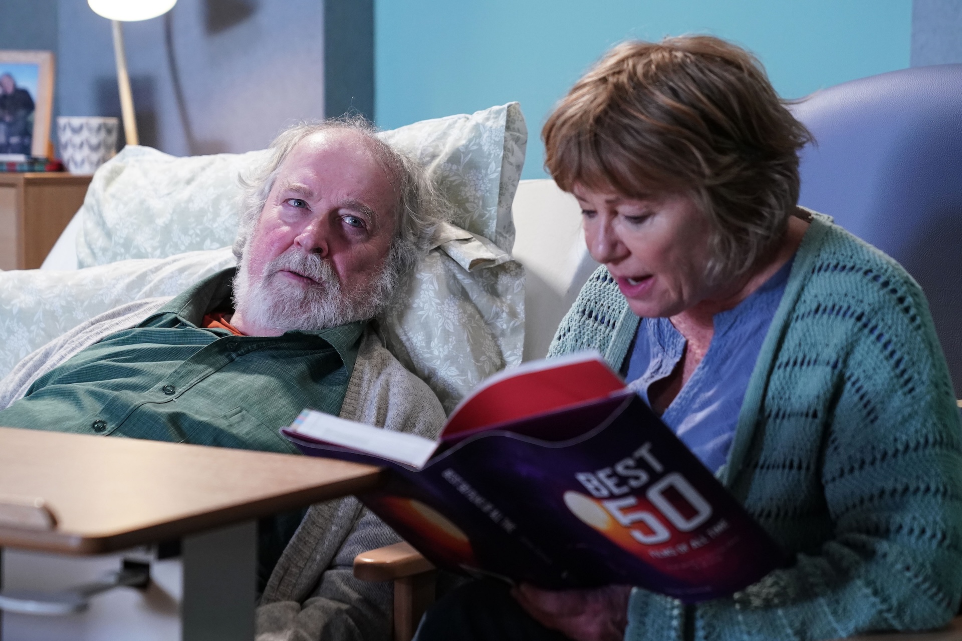 Julie reading to Nigel who lies in bed 
