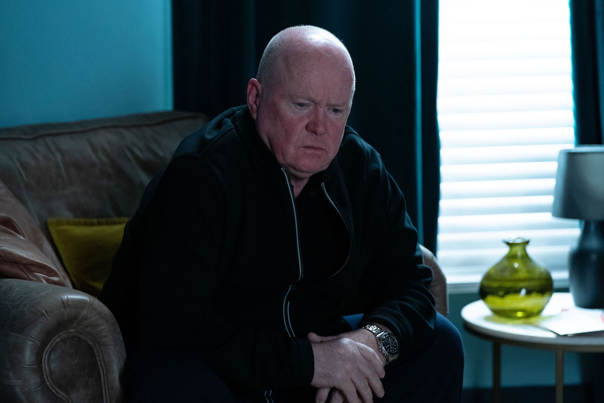 Phil sitting in his armchair looking glum in EastEnders