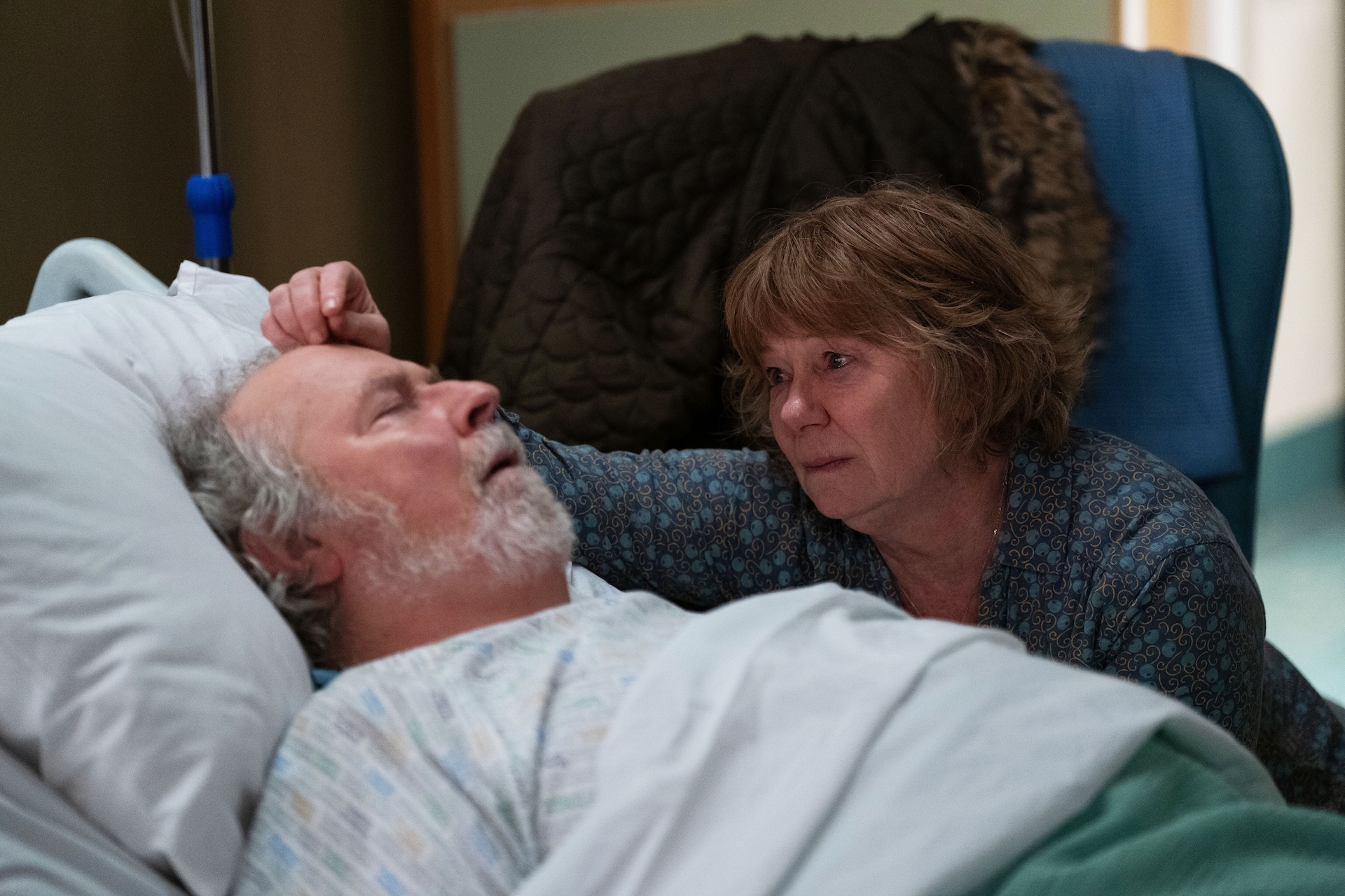 Julie stroking Nigels head as he lies in a hospital bed 