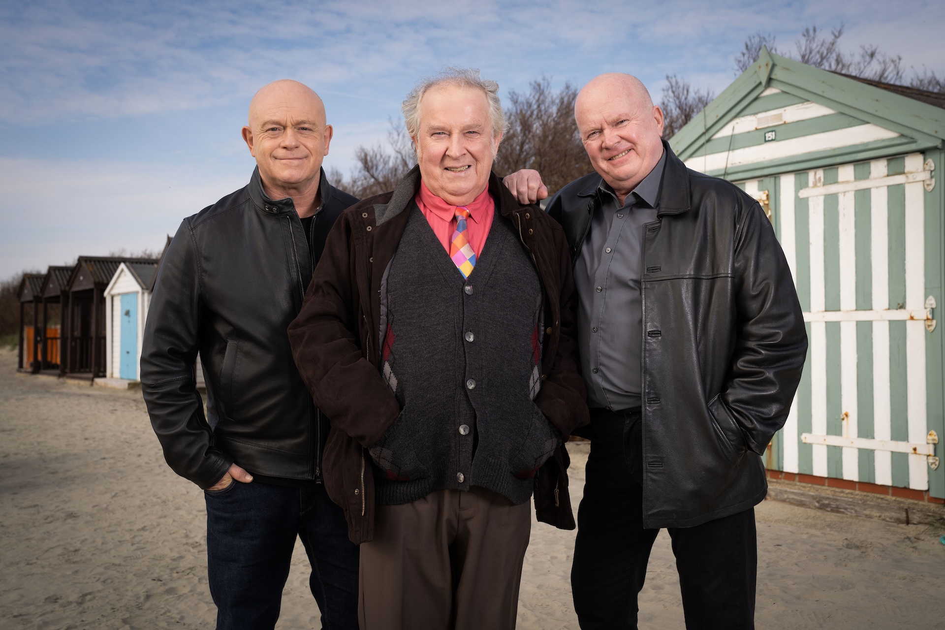 Nigel, Grant and Phil all standing in a row in front of beach huts 