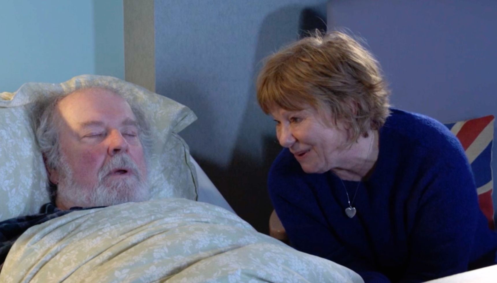 Julie sitting by Nigel's bed as he sleeps