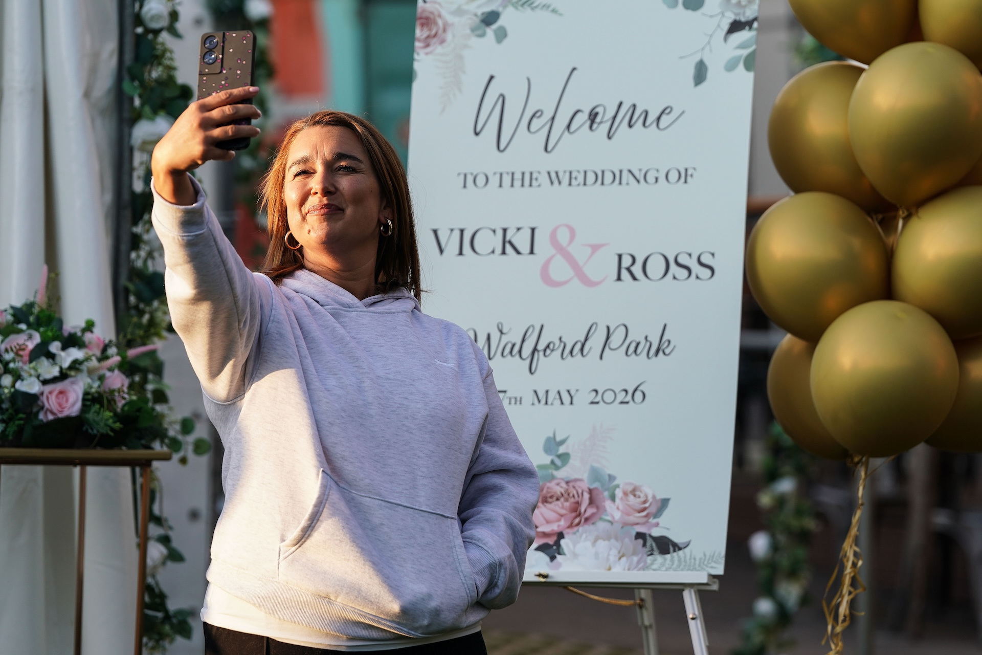 Vicki taking a photo in front of her wedding sign 