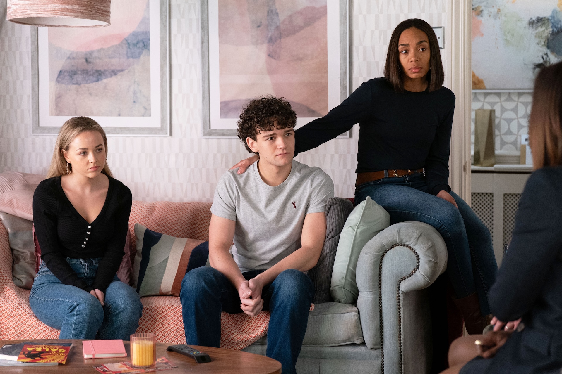 Amy and Ricky sitting on the sofa with Chelsea looking sad 