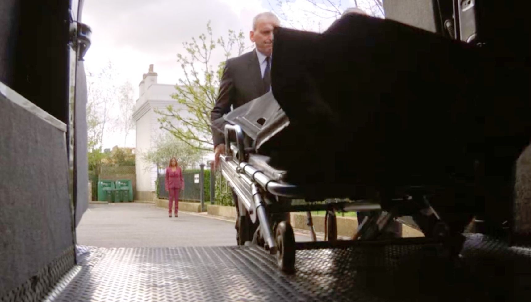 Denise looking upset as she watches Eddie's body being put in a private ambulance 
