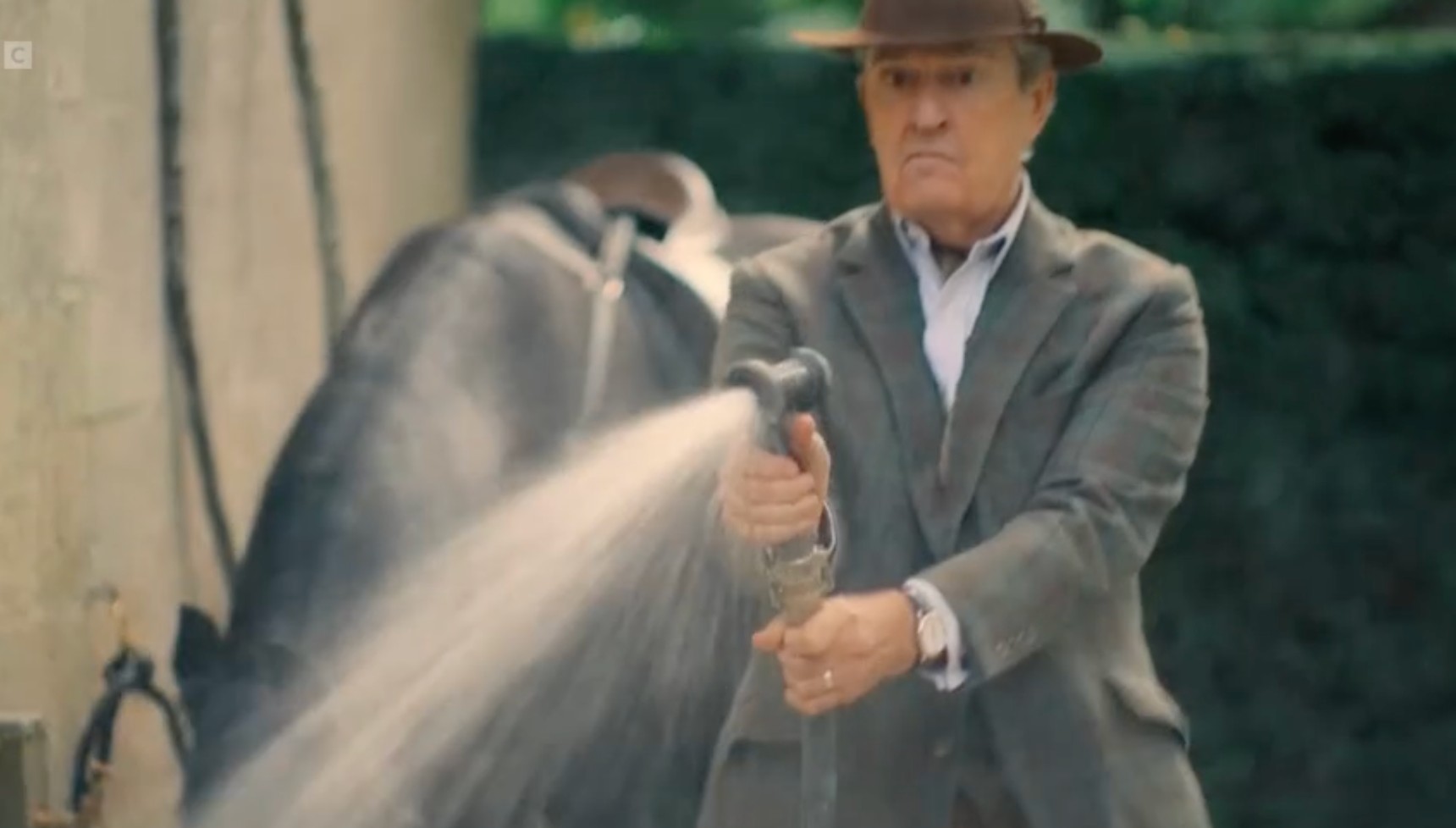 Rupert Everett spraying a hose in Rivals series 2