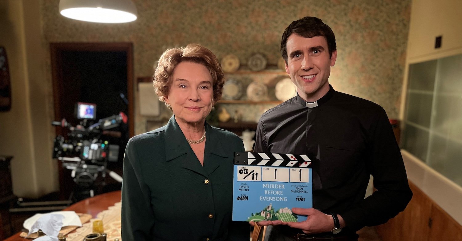 A behind-the-scenes pic showing two members of the Muder Before Evensong cast – Amanda Redman, who plays Audrey Clement, and Matthew Lewis, who plays Canon Daniel Clement, with a clapperboard