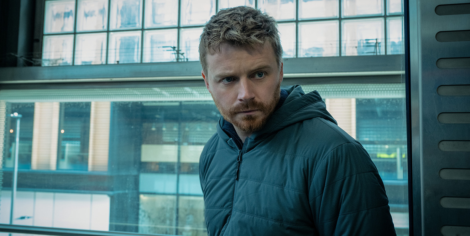 A close up of Jack Lowden wearing a hooded jacket in Slow Horses season 5.