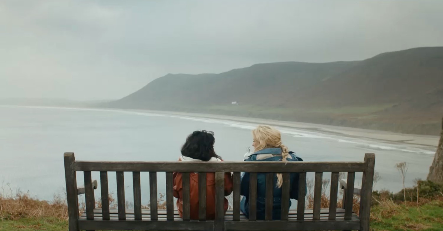 Ria and Fran sit on a bench on Gower Peninsula