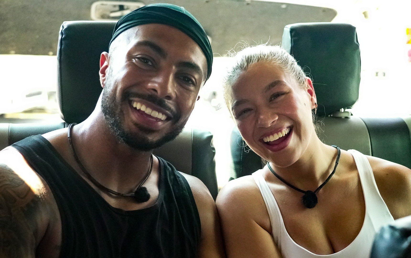 A smiling couple take a selfie in the back of a car