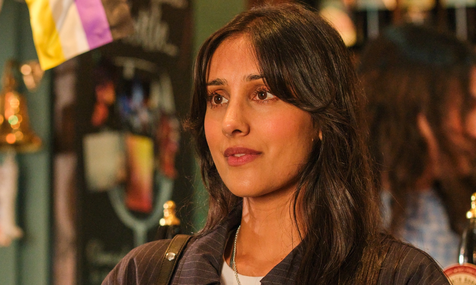 Taj Atwal as Nisha Lal standing in the pub, smiling