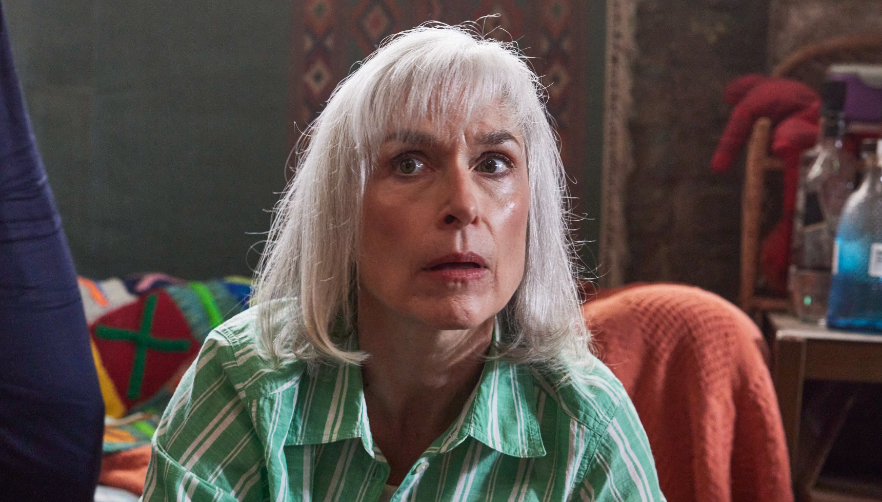 Amelia Bullmore as Yvonne Vaux wearing a green top and looking nervous