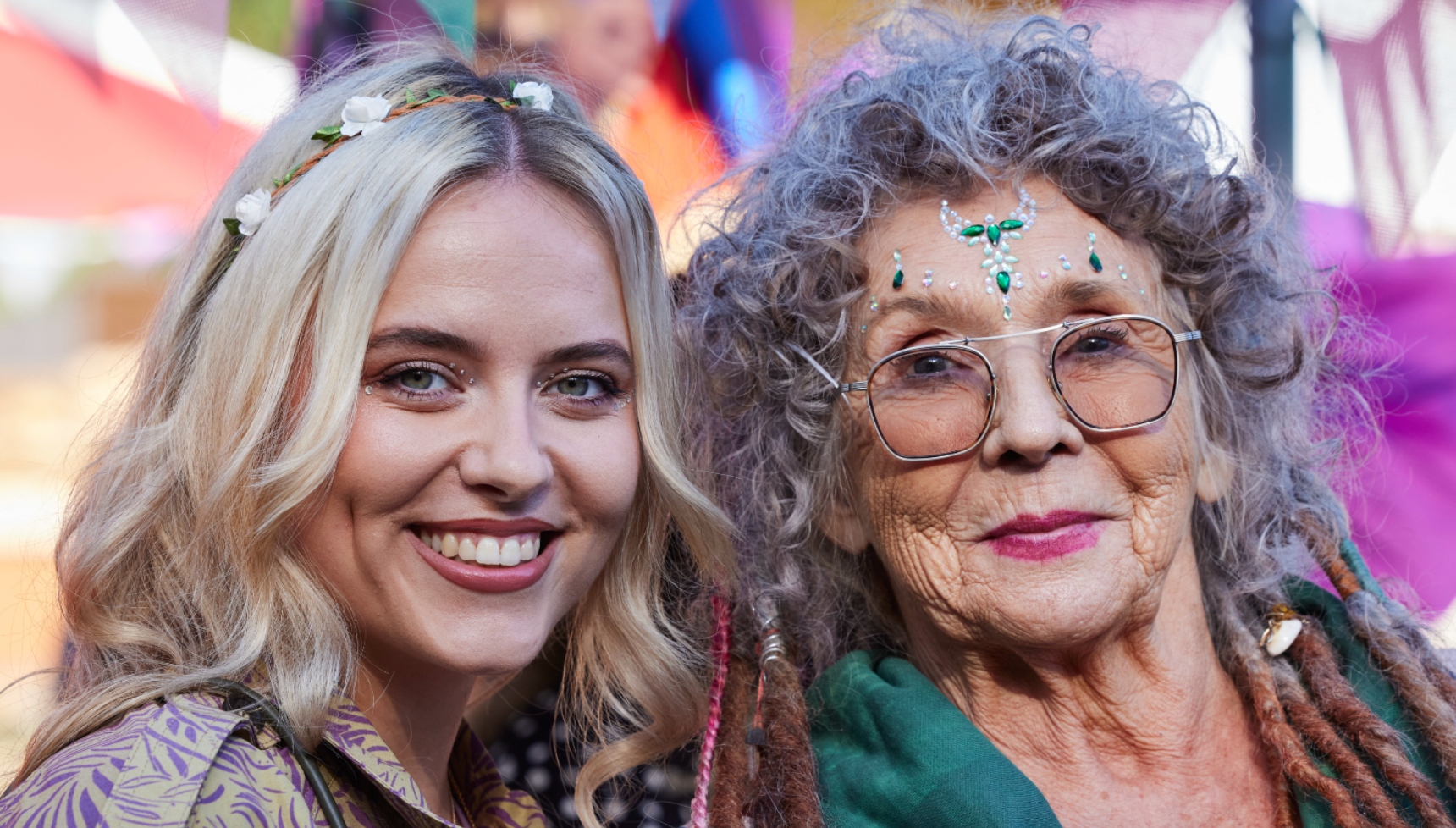 Sue Johnston as Auntie Mary and Shannon Lavelle as Chloe wearing festival head bands and smiling.