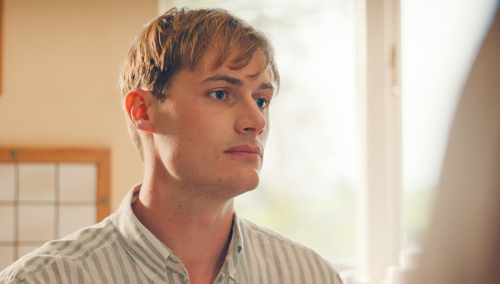 Jonny Green as Tom wearing a cream shirt and looking sad