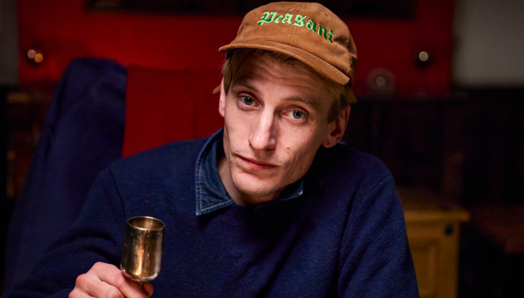Charlie Cooper in a beige cap holding up a goblet