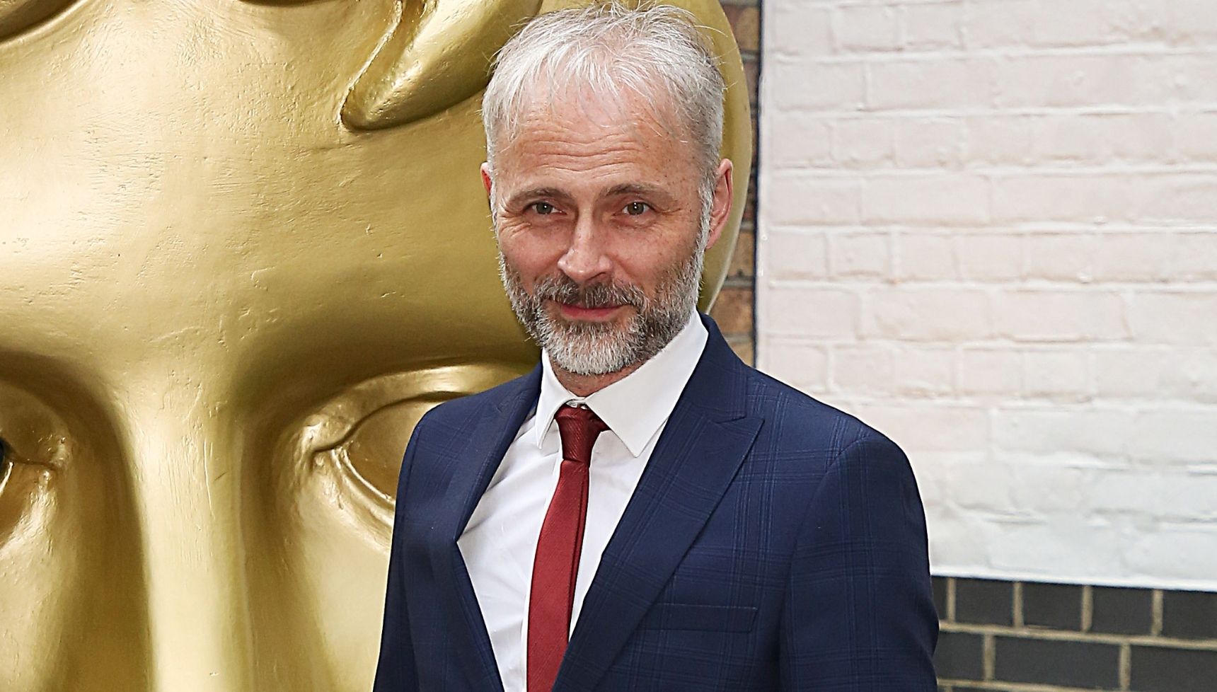 Mark Bonnar next to giant BAFTA