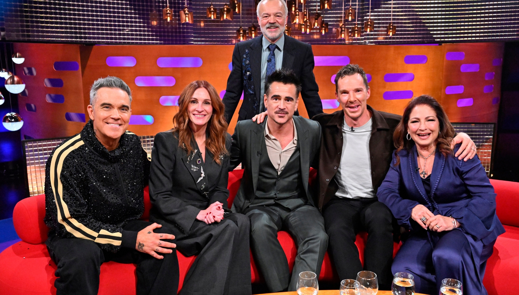 Graham Norton with guests Robbie Williams, Julia Roberts, Colin Farrell, Benedict Cumberbatch and Gloria Estefan. Grahm is behind while the guests sit on the sofa