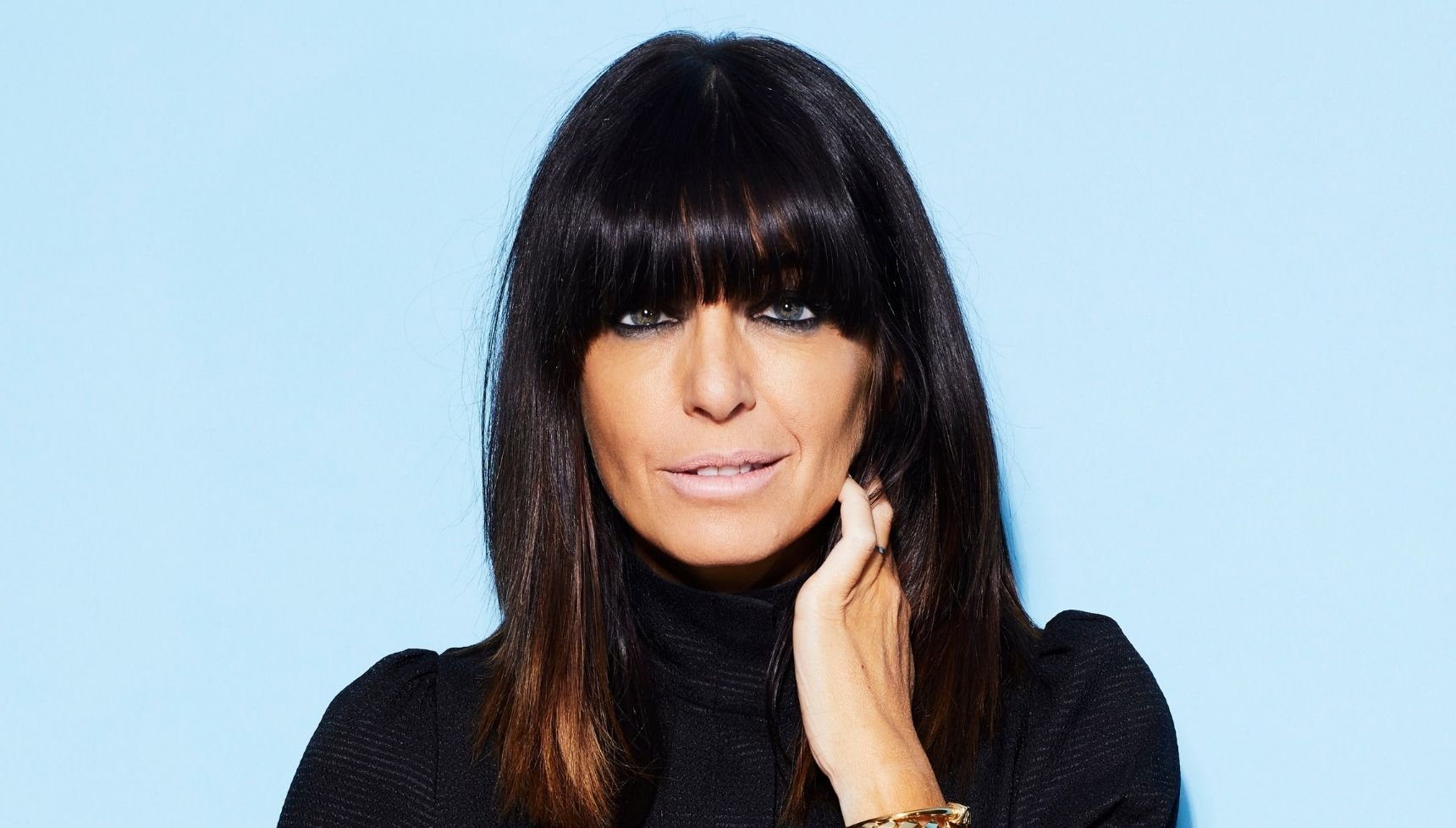 Claudia Winkleman stands against a blue background