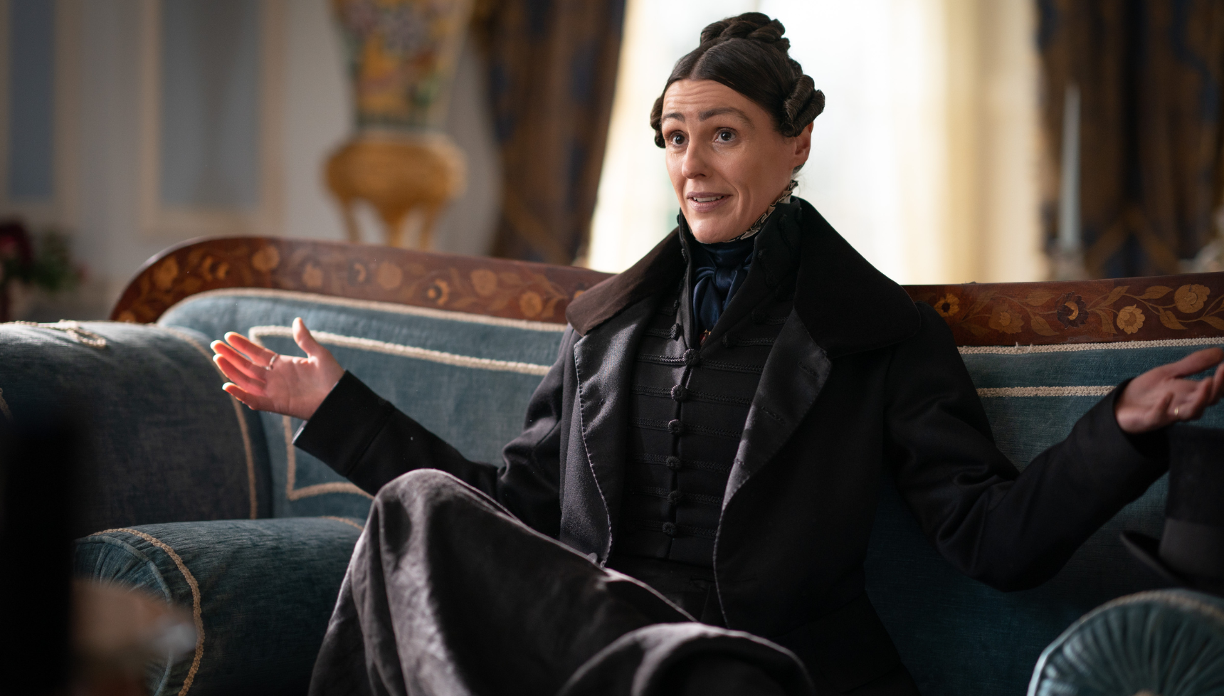 Suranne Jones dressed up in a suit and sat on a sofa in Gentleman Jack,