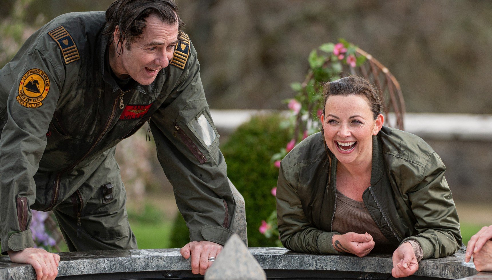 A man and a woman laugh even though their heads are wet