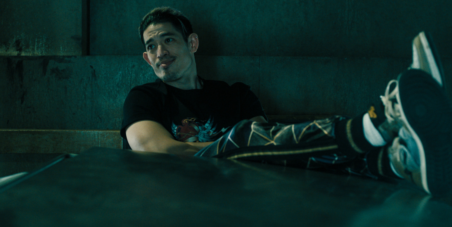 Roddy Ho sat in a chair with his legs on the table in Slow Horses season 5 episode 3.