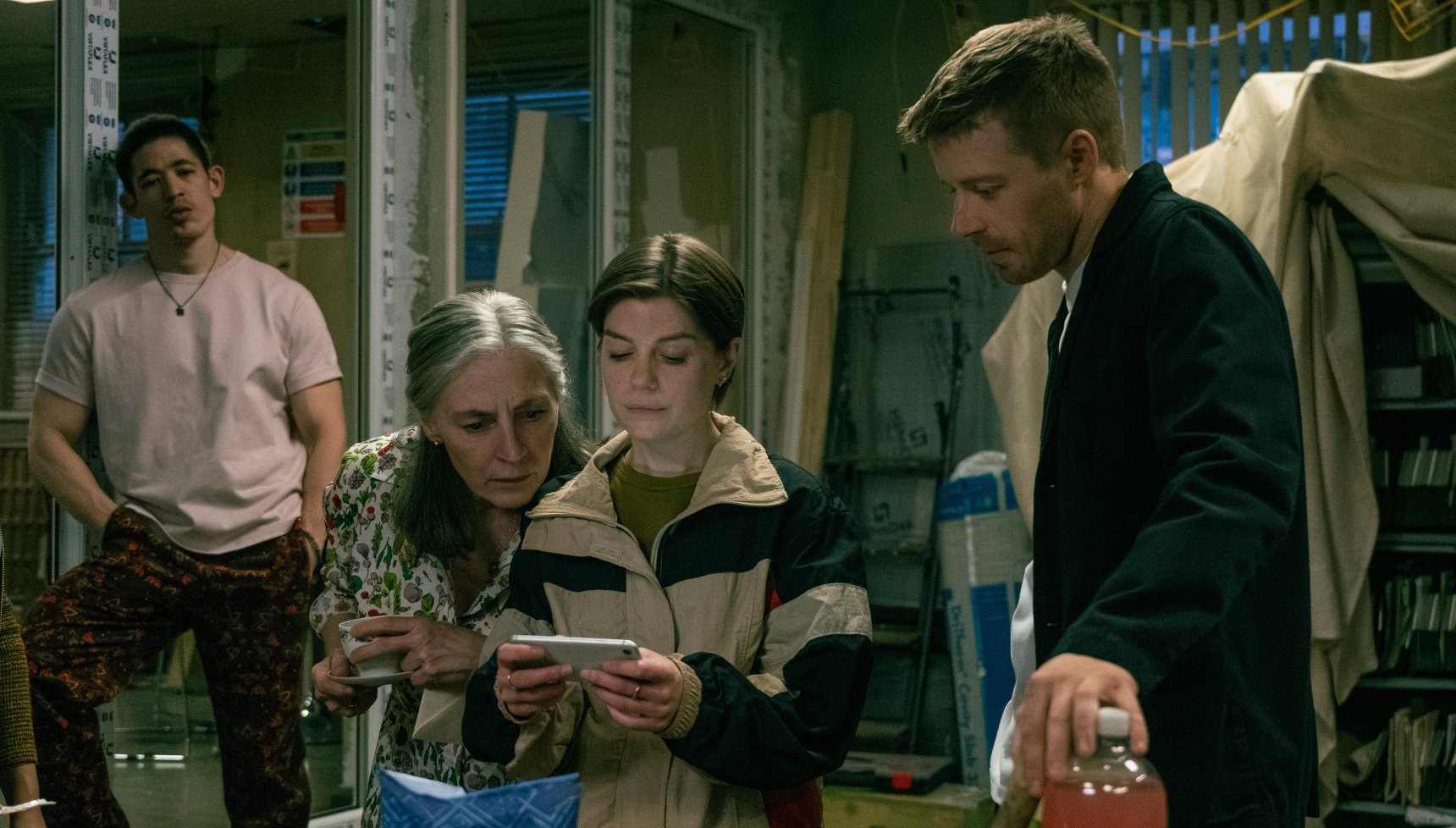 Slow Horses Roddy, Catherine, Shirley and River looking at a phone in Slow Horses.