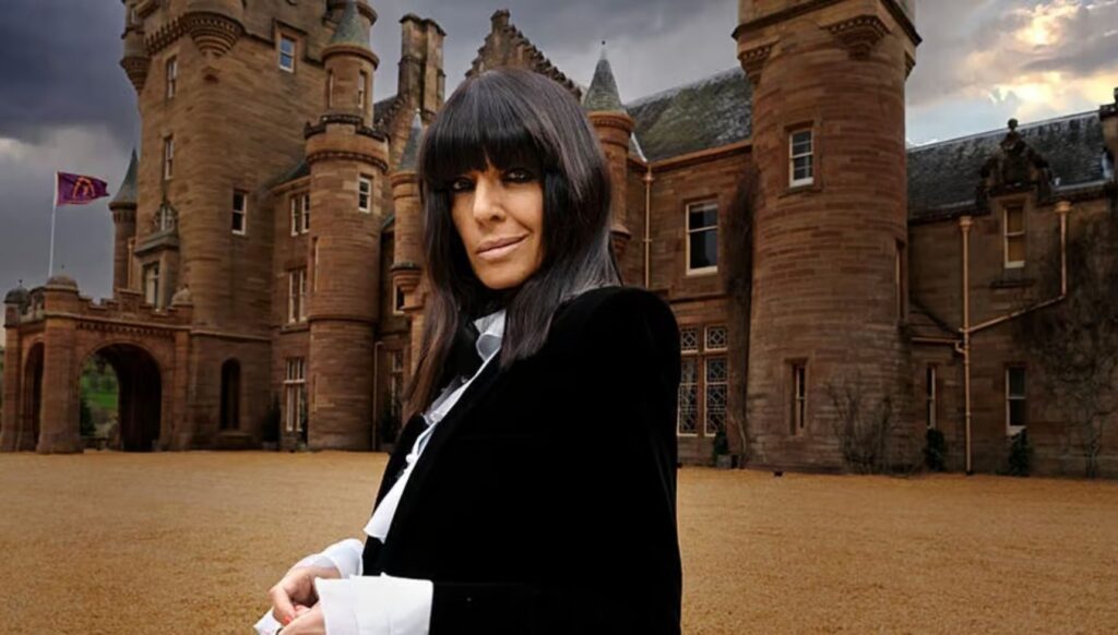 Claudia Winkleman smirking outside The Traitors' castle.