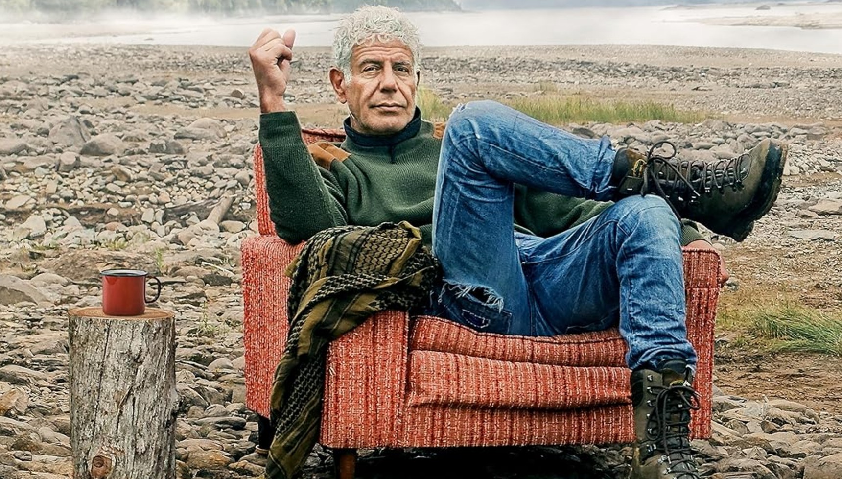 Anthony Bourdain sitting on a sofa seat in a field