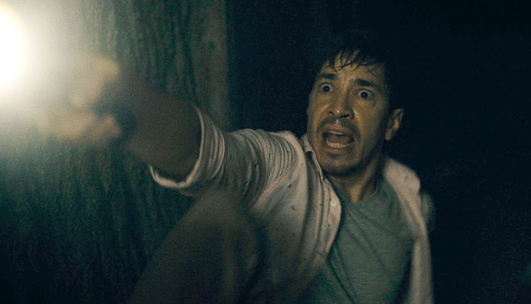 Justin Long pointing a flashlight and screaming in Barbarian