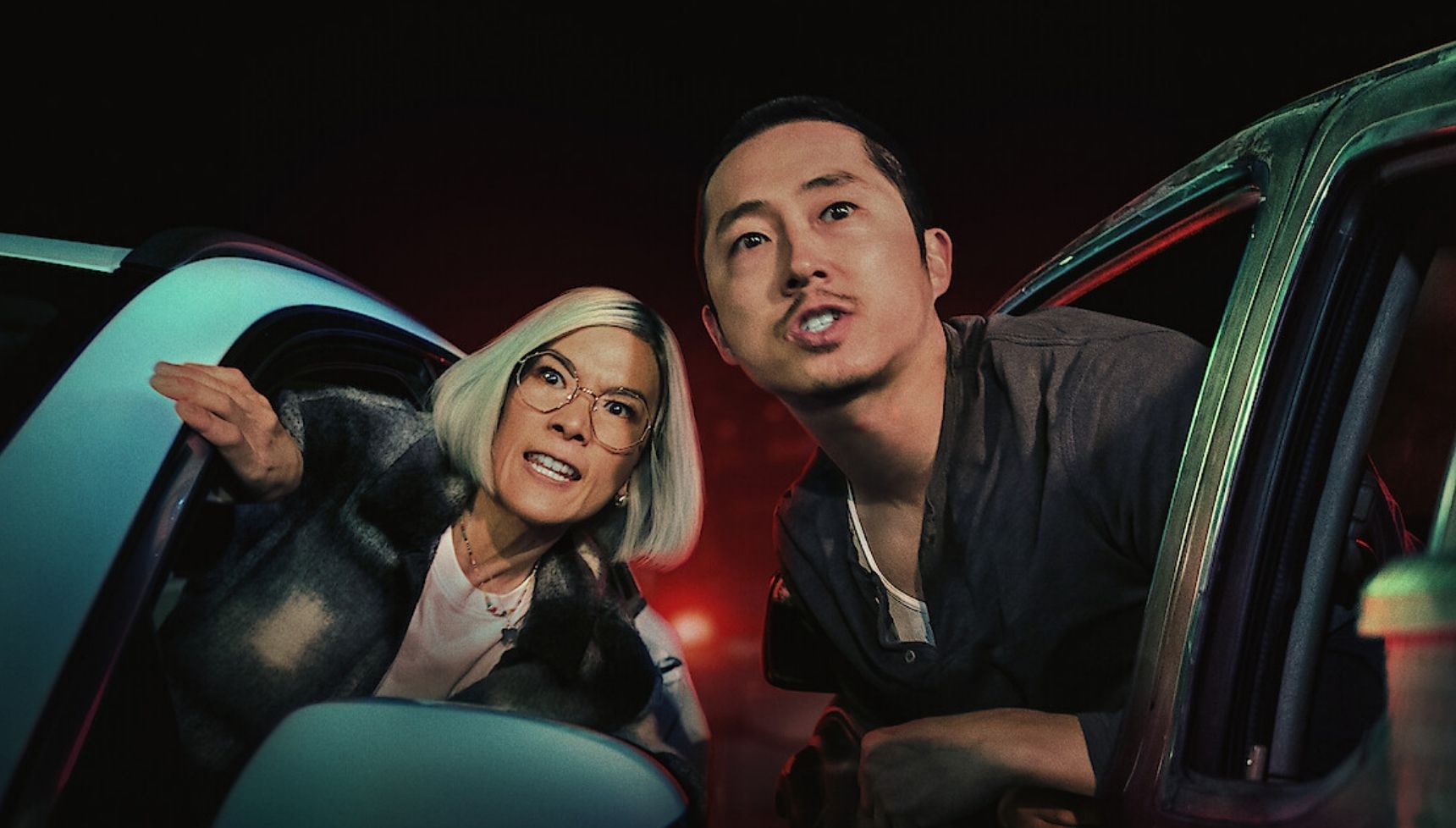 Ali Wong and Steven Yeun leaning out of their cars and shouting at someone in Beef