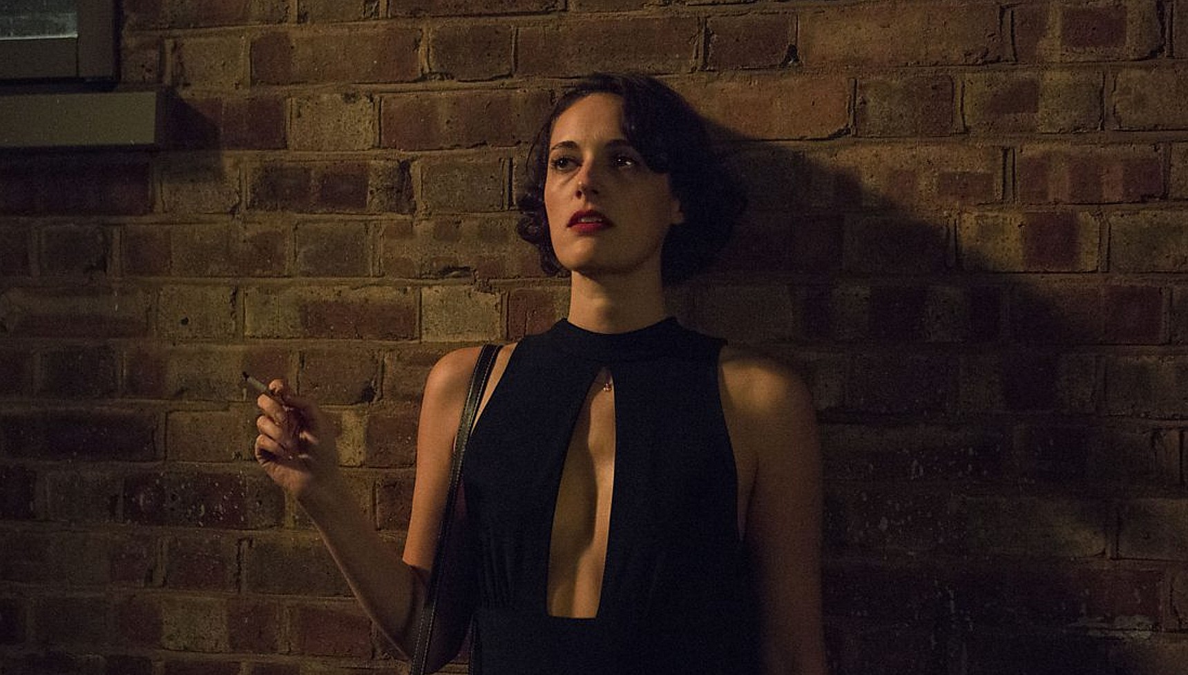 Phoebe Waller-Bridge leaning against a wall smoking a cigarette in Fleabag