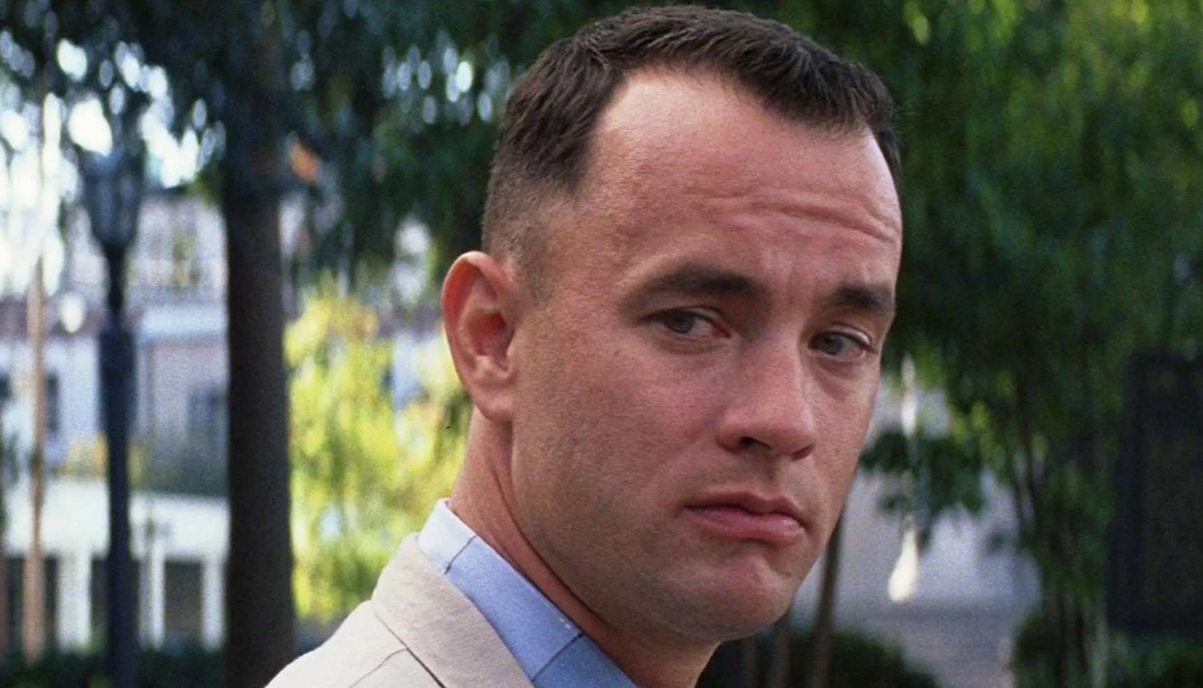 Tom Hanks looking at someone as he sits on a bench in Forrest Gump