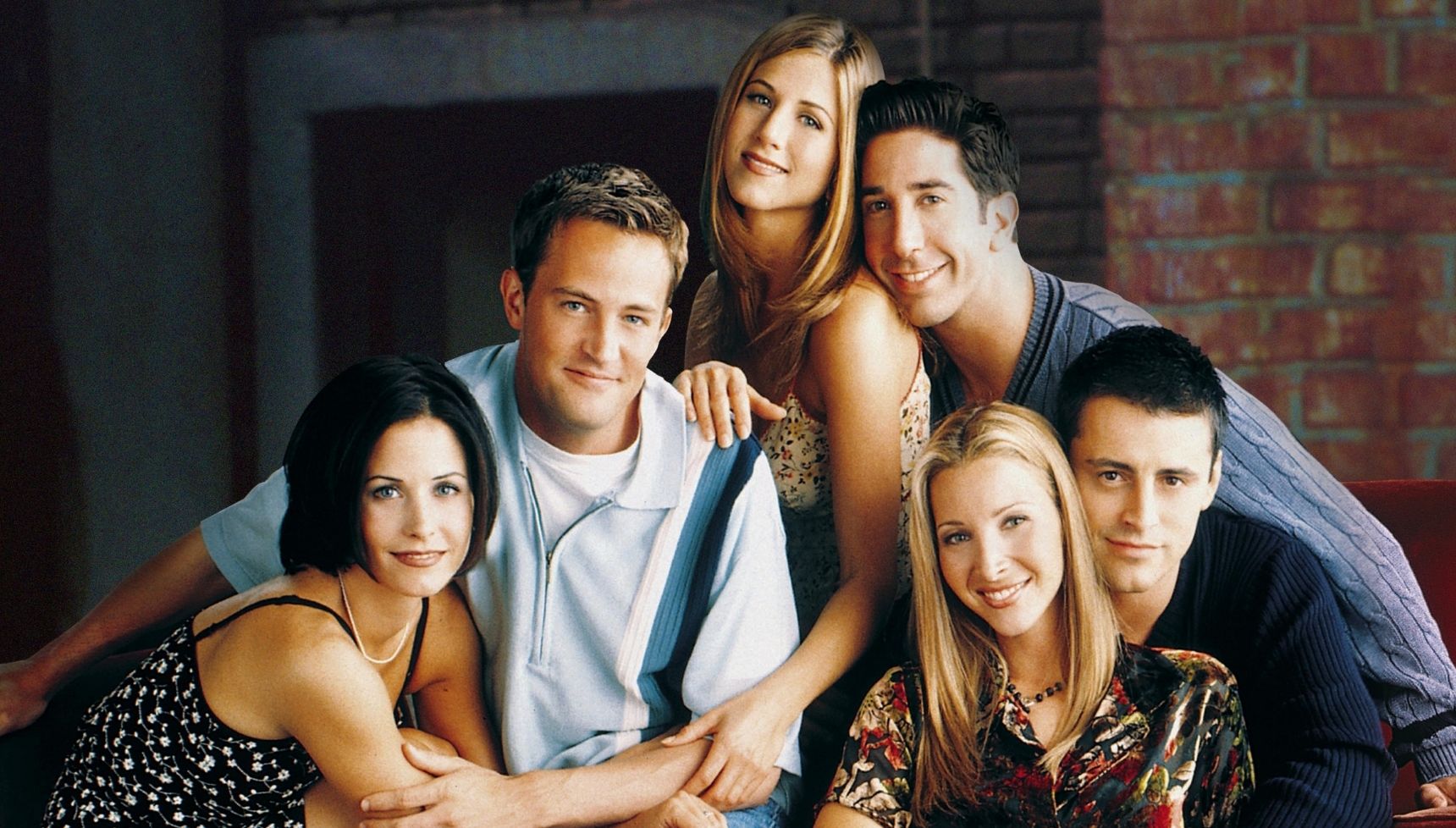 The cast of Friends sitting together and hugging