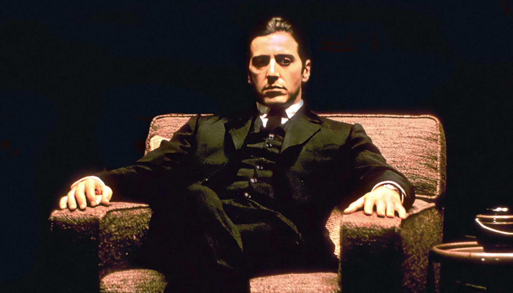 Al Pacino sitting in a chair in a poster for The Godfather movies