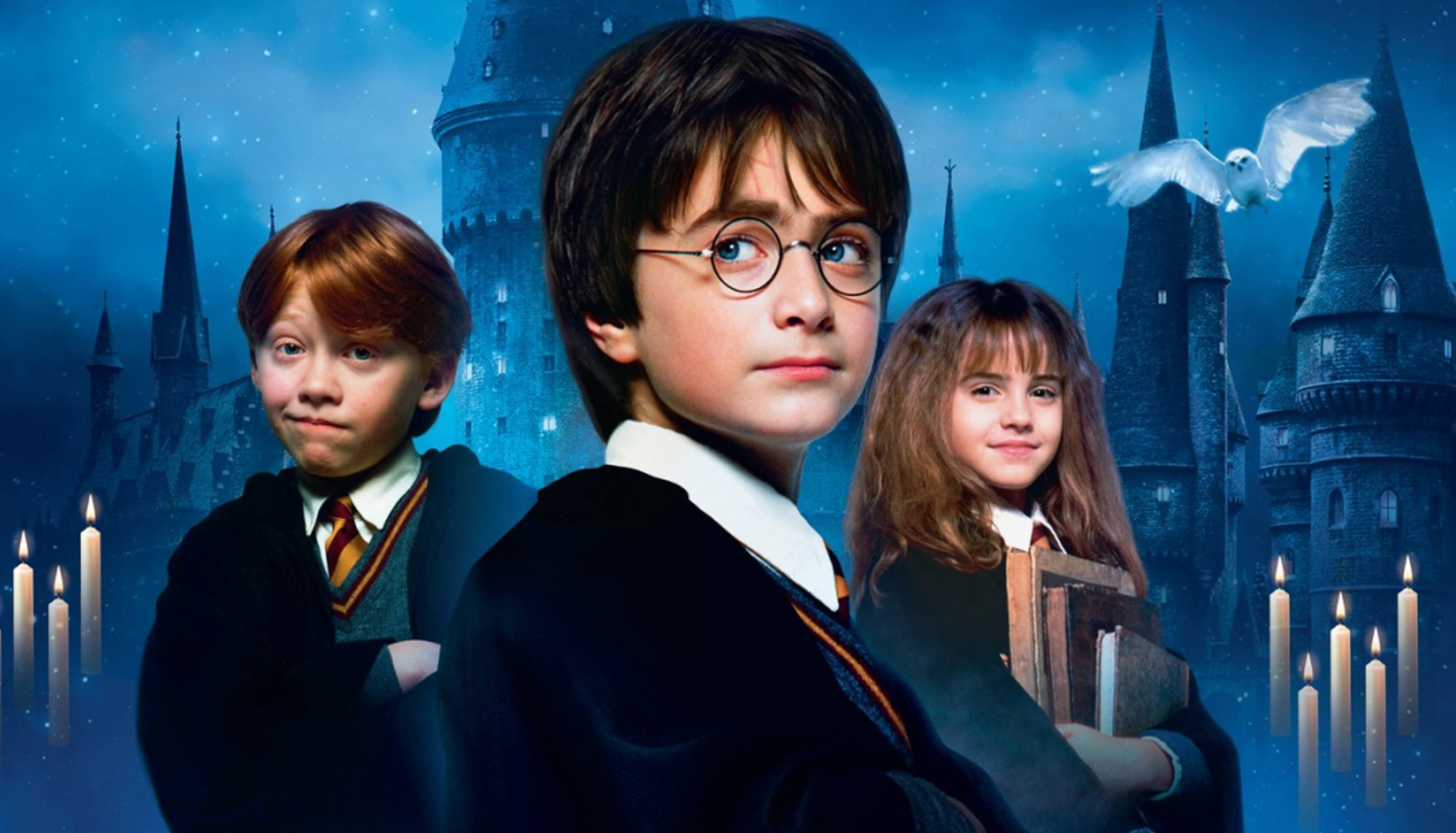 Rupert Grint, Daniel Radcliffe and Emma Watson in their Hogwarts uniforms as a white owl flies behind them