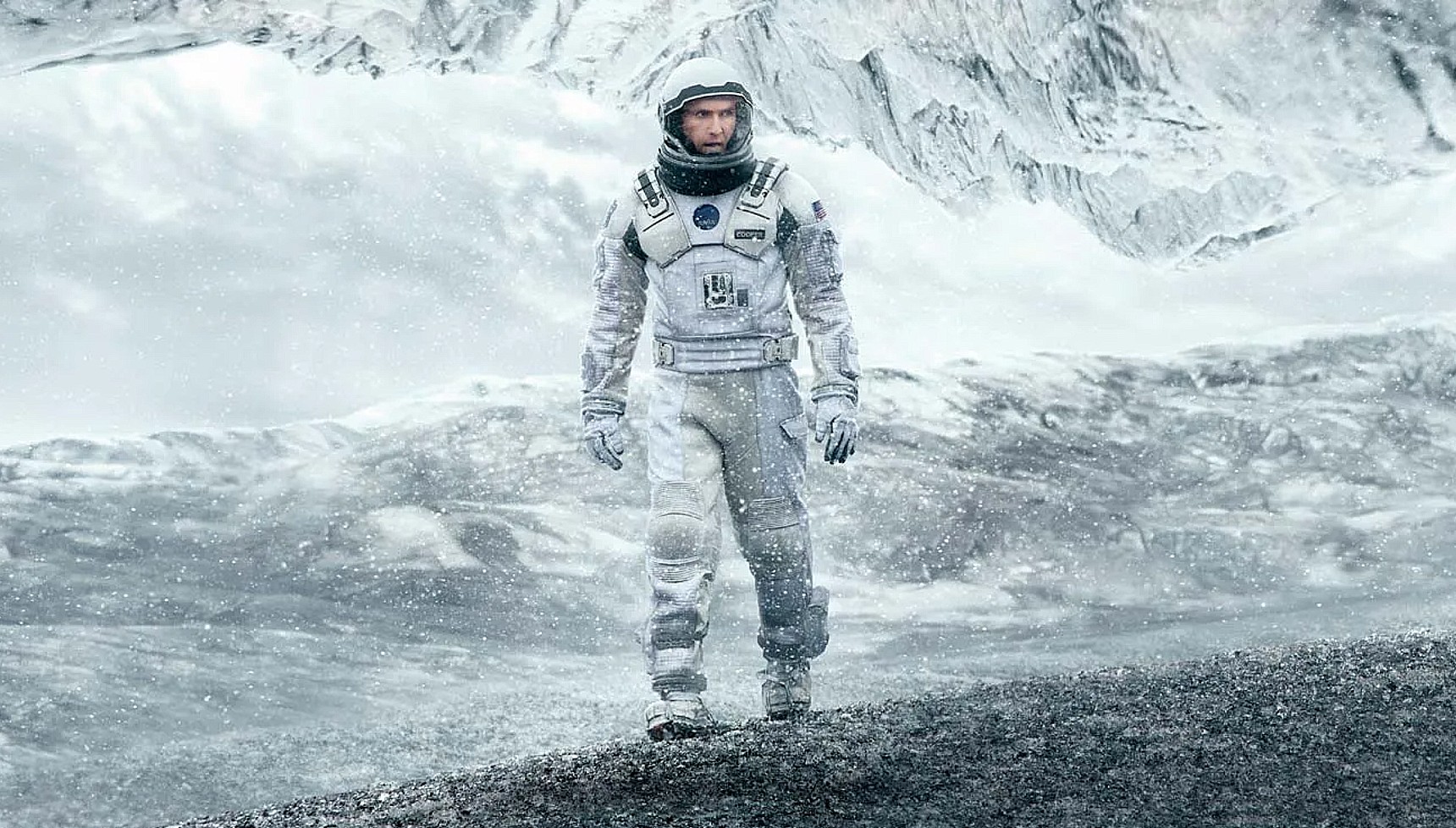 Matthew McConaughey in an astronaut suit walking on a snowy surface in Interstellar