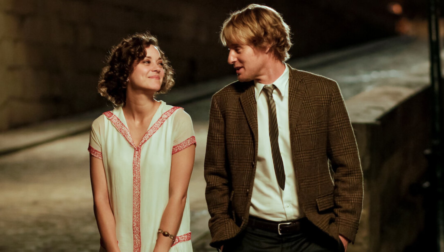 Marion Cotillard and Owen Wilson walking along the banks of a river in Paris