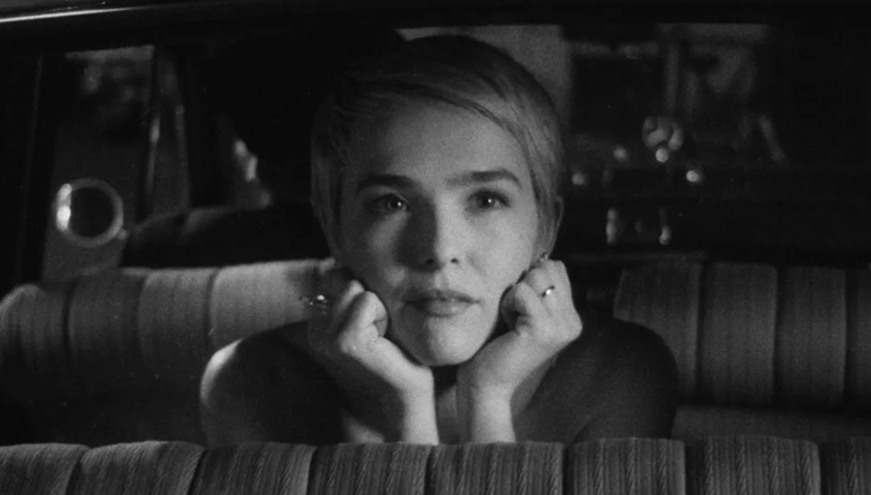 Zoey Deutch sitting in the back of a car in a black and white image from Nouvelle Vague