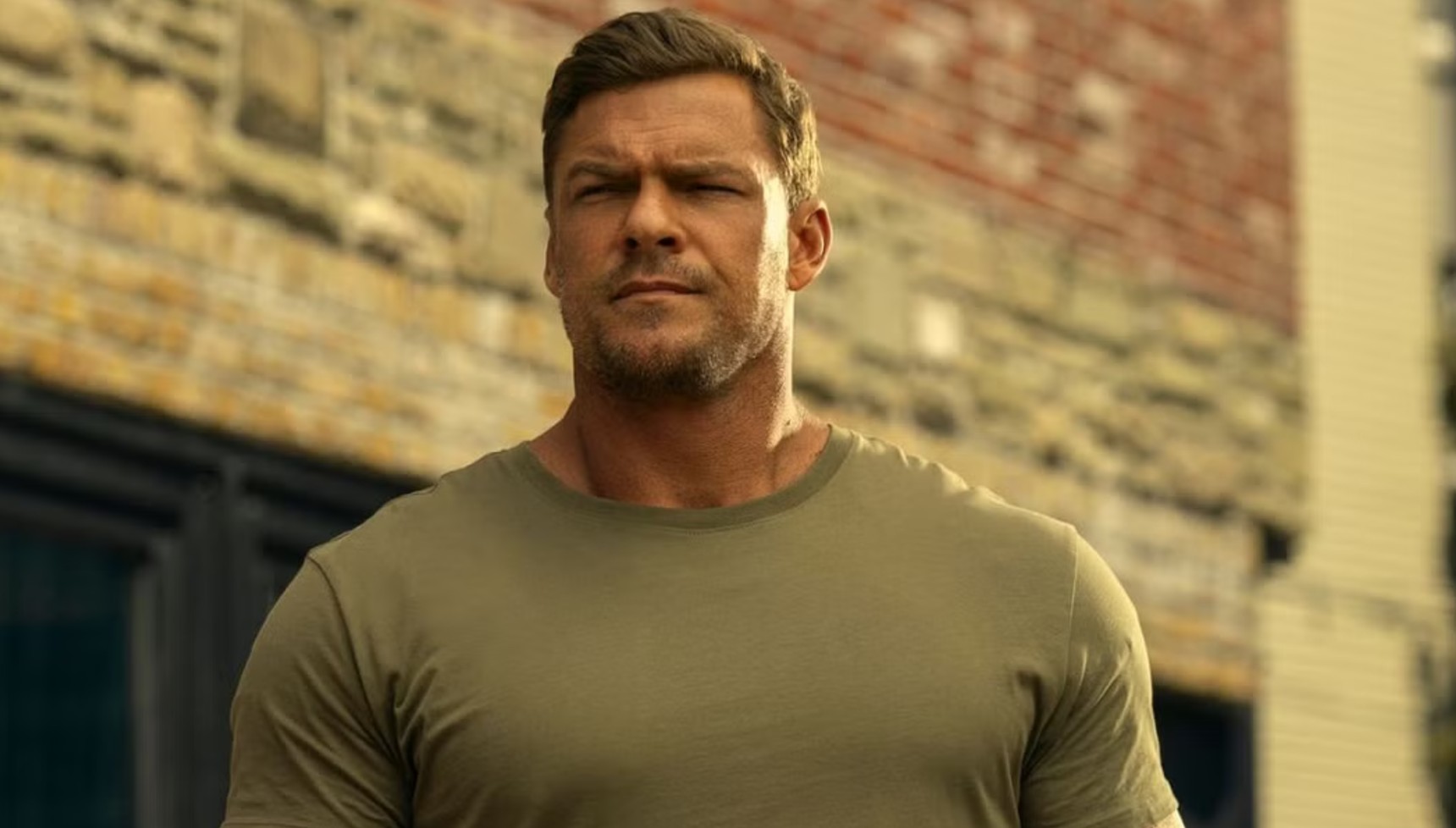 Alan Ritchson in a pale green t-shirt in Reacher