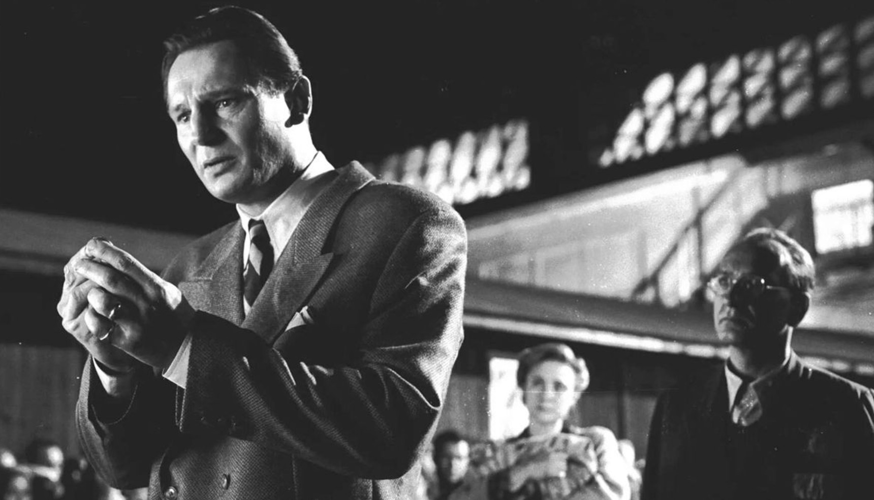Liam Neeson clasping his hands in a black and white image from Schindler's List